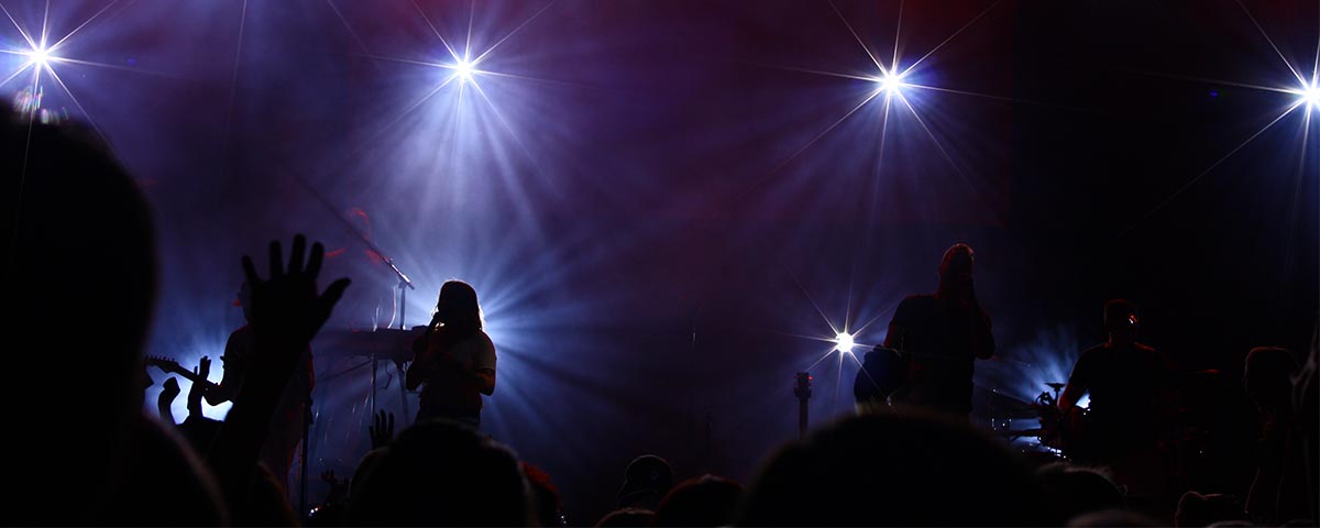Band auf dunkler Bühne mit weissem Scheinwerferlicht
